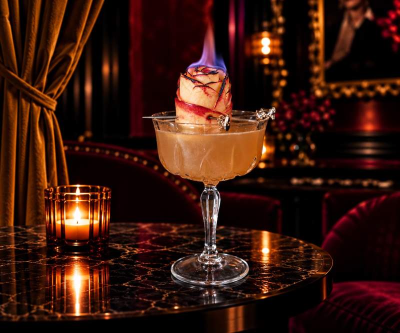 A cocktail glowing under candlelight on a marble table inside Bad Rabbit.